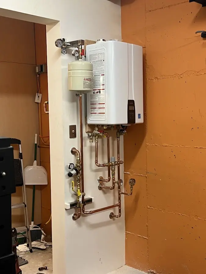 Plumbing technician inspecting water heater connections in Warm Beach